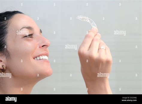 A Smiling Woman Holding Invisible Braces Dental Correction Mobile