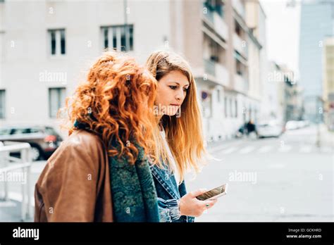 Zwei junge schöne kaukasischen Blonde und Rothaarige Frauen Freunde ein Spaziergang im Freien in