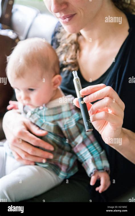 Woman Smoking Electronic Cigarette Beside A Baby Stock Photo Alamy