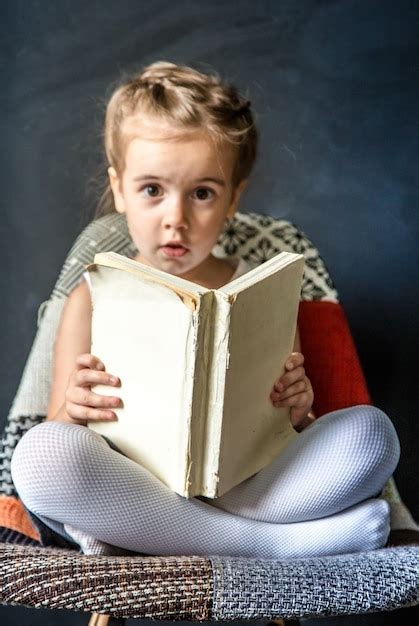 Jolie petite fille assise sur une belle chaise avec un livre à la main