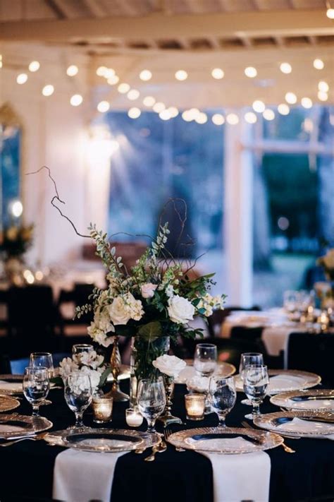 An Elegant Black And White Table Setting With A Lush Floral Centerpiece Gold Cutlery And