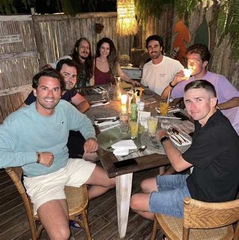 A Group Of People Sitting Around A Wooden Table