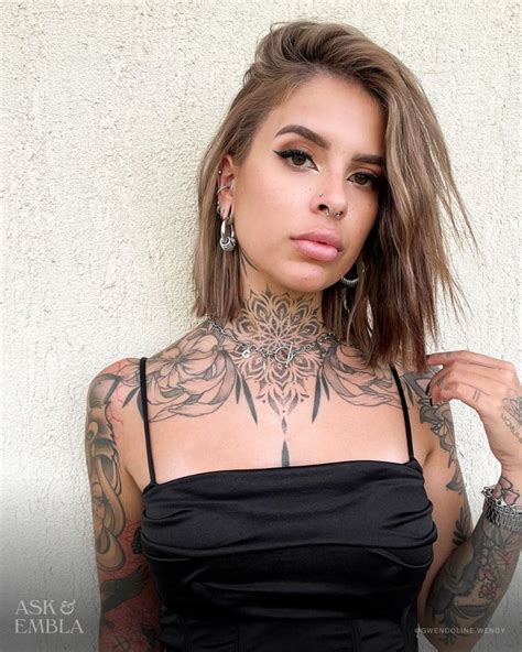 A Woman With Tattoos On Her Chest Posing For The Camera While Wearing A