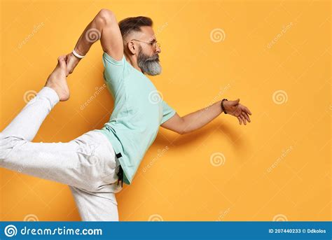 Elderly Yogi Man With Naked Torso In Brown Pants Is Practicing Yoga Standing On His Hands