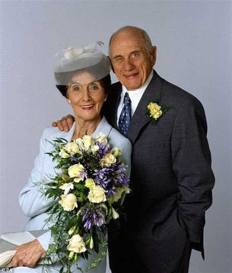 an older couple posing for a photo with flowers in front of their heads and arms