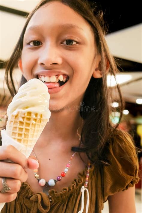 Southeast Asian Teen Girl Enjoys Eating Vanilla Ice Cream Cone At Mall