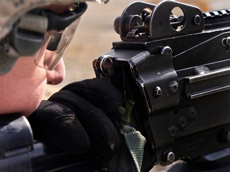 A soldier scans his sector of fire before engaging targets with an M249 ...