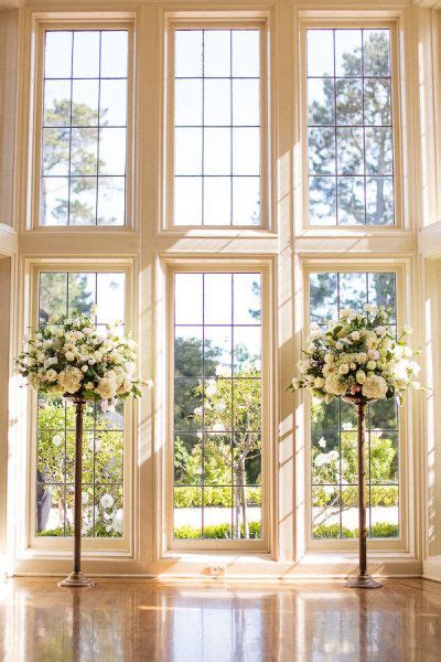 Two Tall Vases Filled With White Flowers On Top Of A Wooden Floor Next