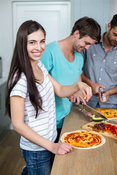 유토이미지 Portrait Of Young Woman Preparing Pizza On Table In Kitchen