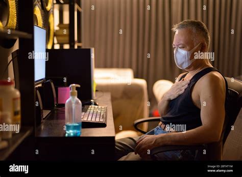 Stressed Mature Japanese Man With Mask Getting Sick While Working
