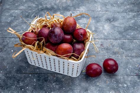 Frische pflaumen im weißen korb auf grau Kostenlose Foto