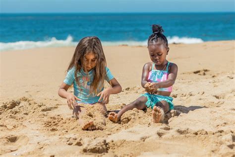 A Young Girls Playing Sand On The Beach · Free Stock Photo