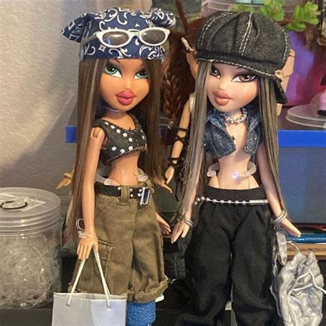 Two Dolls Standing Next To Each Other Holding Shopping Bags And Looking