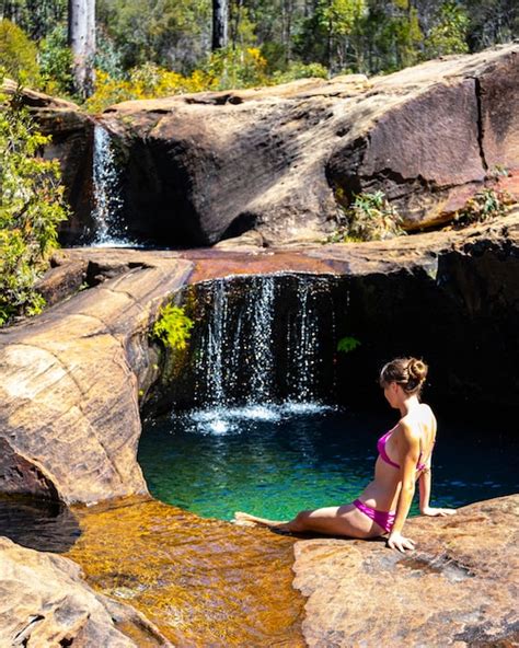 Premium Photo | Beautiful girl in pink bikini sits by natural rock pool with waterfalls in ...