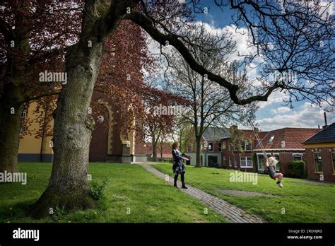 A Mother Pushes The Swing On Which A Girl With Flowing Blonde Hair Is Sitting Stock Photo Alamy