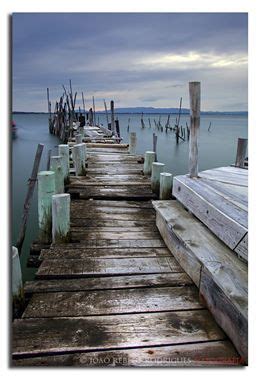 A Wooden Dock With Water And Boats In The Background