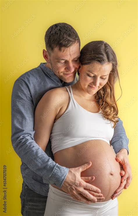 Smiling Parents Holding Naked Round Pregnant Belly Of Mother With Thier Hands In Last Month Of