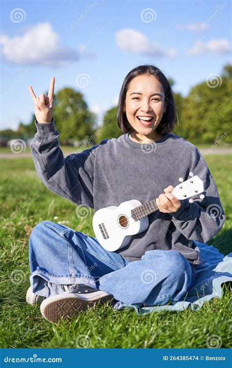 Happy Asian Girl Playing Ukulele In Park Showing Rock N Roll Heavy