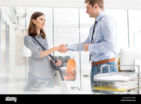 Confident Business People Shaking Hands In Office Stock Photo Alamy