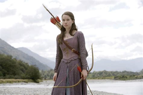 A Woman With Bow And Arrow Standing In Front Of Water