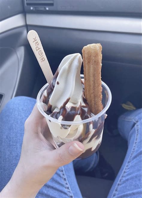 A Person Is Holding An Ice Cream Sundae In Their Hand While Sitting In