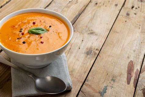 Horizontal Image Of Bowl Of Tomato Soup With Garnish And Spoon On Wood