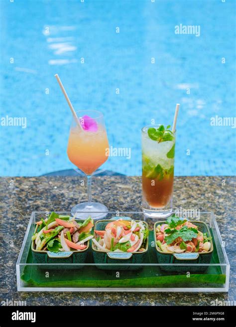 Orange Cocktail And Mojito At A Swimming Pool On A Luxury Vacation In Thailand With Thai Snacks