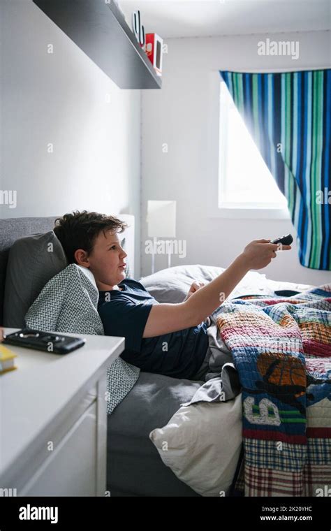 Boy with remote control watching TV in bed Stock Photo - Alamy