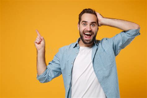 Excited Young Man In Casual Blue Shirt Posing Isolated On Yellow Orange