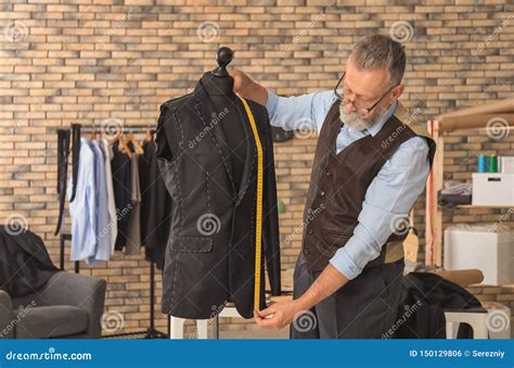 Mature Tailor Taking Measurements Of Jacket On Mannequin In Atelier