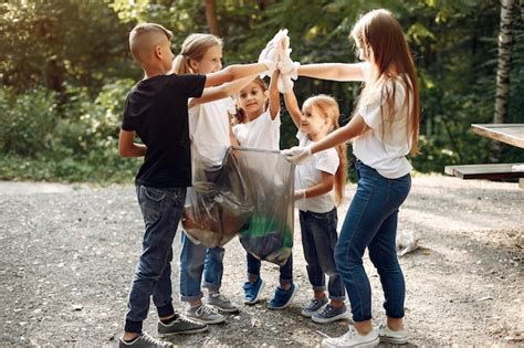 Los Ni Os Recogen Basura En Bolsas De Basura En El Parque Foto Gratis