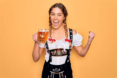 Beautiful Blonde German Woman With Blue Eyes Wearing Octoberfest Dress Drinking Jar Of Beer