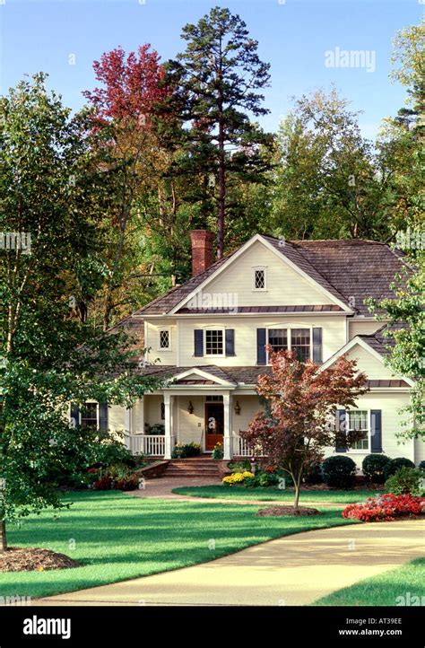 A White Two Story Upper Middle Class Suburban House With A Concrete Driveway On A Well