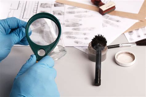 Forensic Expert Using A Magnifying Glass Examines Fingerprints On