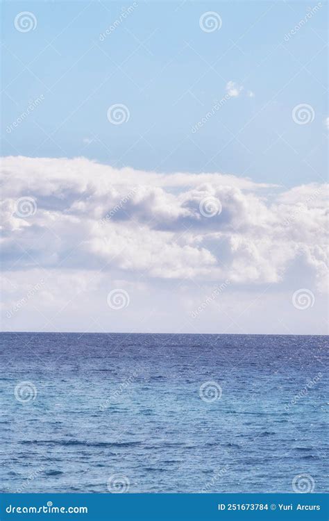 A Cloudy Blue Sky And Peaceful Calm Ocean Separated By A Beautiful