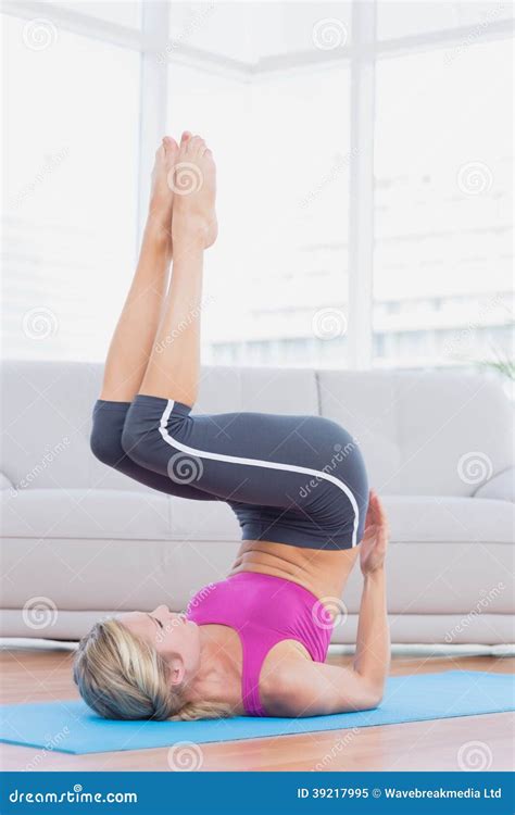 Slim Blonde Lifting Her Legs And Hips On Exercise Mat Stock Image