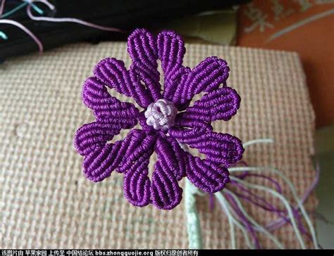 A Close Up Of A Purple Flower On A Piece Of Cloth Next To Some Thread