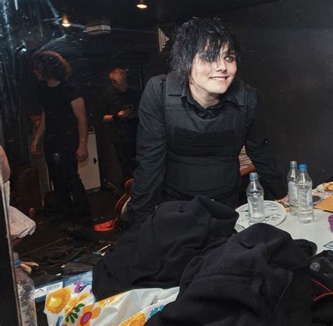 A Man With Black Hair Standing In Front Of A Mirror Next To A Table