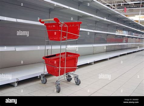 Carrito de compras con cestas vacías en las estanterías vacías del