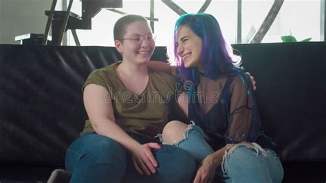 Two Young Lesbian Girls Sitting On The Couch Looking At The Camera