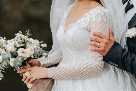 Wedding Portrait A Brunette Bride In A Long Dress And A Groom In A Classic Suit Pose Under A