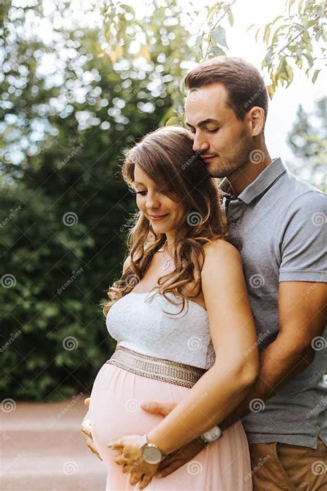 Husband Is Embracing His Beautiful Pregnant Wife From Behind Stock