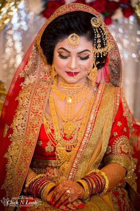 A Woman In A Red And Gold Bridal Outfit Sitting Down With Her Hands On Her Knees