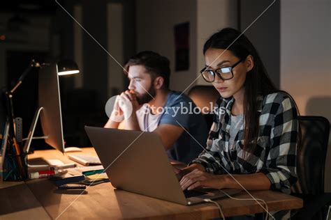 Image Of Two Business People Working With Laptop And Computer Late At