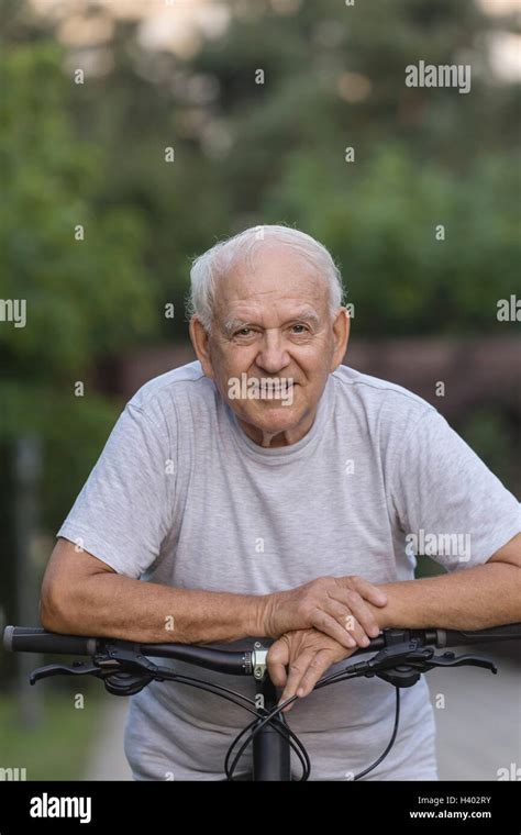 Portrait Of Senior Man Leaning On Bicycle At Park Stock Photo Alamy