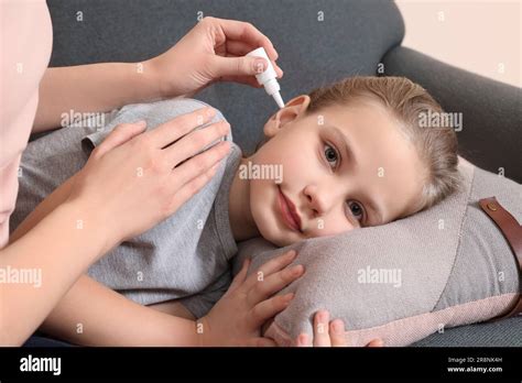 Mother Dripping Medication Into Daughters Ear In Living Room Stock