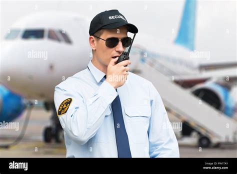 Portrait Of A Male Security Guard Talking On Walkie Talkie At An