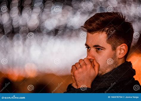 Young Man Trying To Warm Up His Hands At Winter Night Stock Photo