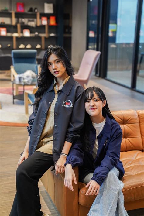 Two Women Sitting On Top Of A Brown Couch