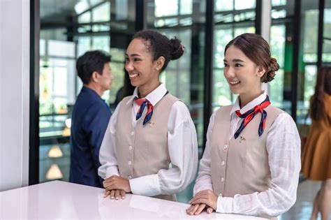 Two friendly female airport ground staffs in airline uniforms standing ...